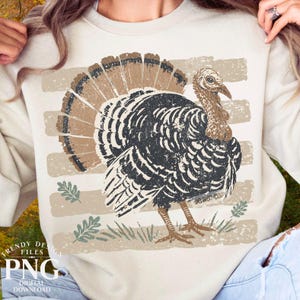 May include: A cream-colored crewneck sweatshirt featuring a distressed graphic of a turkey in shades of black, brown, and tan. The design includes horizontal stripes, small leaf illustrations, and the text DO NOT COPY printed on the turkey's body.