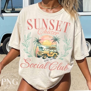 K&ouml;nnte beinhalten: Cremefarbenes T-Shirt mit einem Grafikdesign mit den Worten "Sunset Chaser Social Club". Das Design umfasst einen gelben Jeep, Palmen, ein Surfbrett und eine Sonnenuntergangsszene. Das Shirt hat kurze &Auml;rmel und eine lockere Passform.