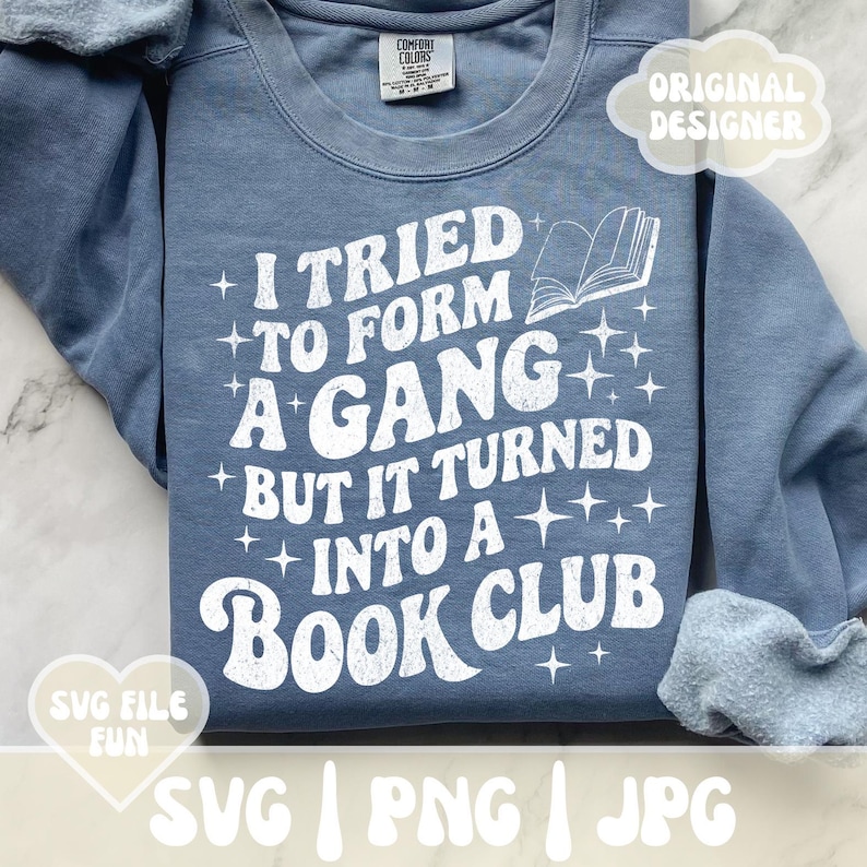 May include: A blue sweatshirt with the text "I tried to form a gang but it turned into a book club" in white. The design includes a book graphic and star accents. The sweatshirt is a Comfort Colors brand.