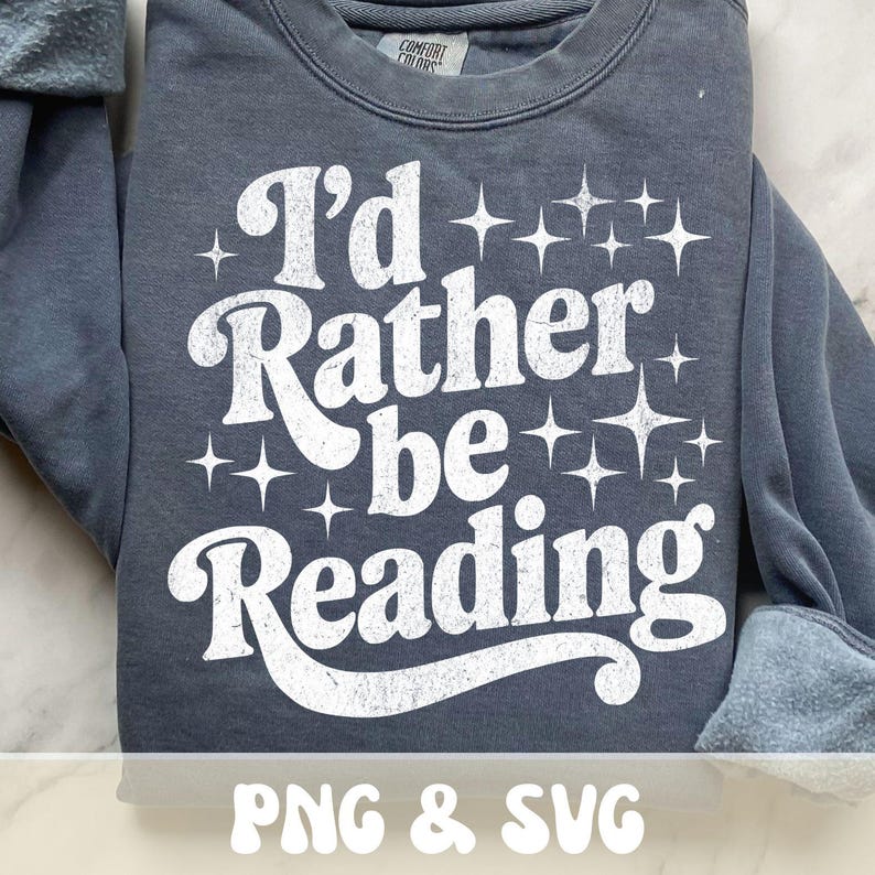 Op de afbeelding: Een donkergrijs sweatshirt met de witte tekst "I'd Rather be Reading" in een retro lettertype. Het ontwerp bevat sterrenburst graphics. Het sweatshirt is van het merk Comfort Colors.