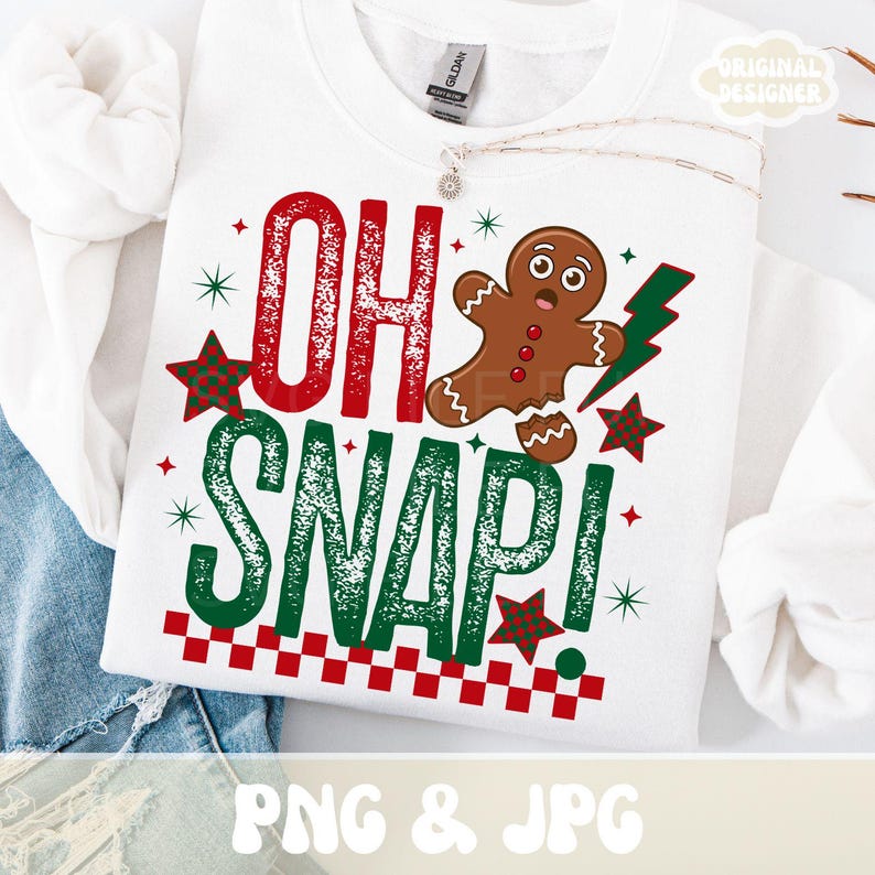 May include: White sweatshirt with the text "OH SNAP!" in red and green, featuring a gingerbread man and star graphics. The design includes a red and white checkered border at the bottom. The words "PNG & JPG" are at the bottom.