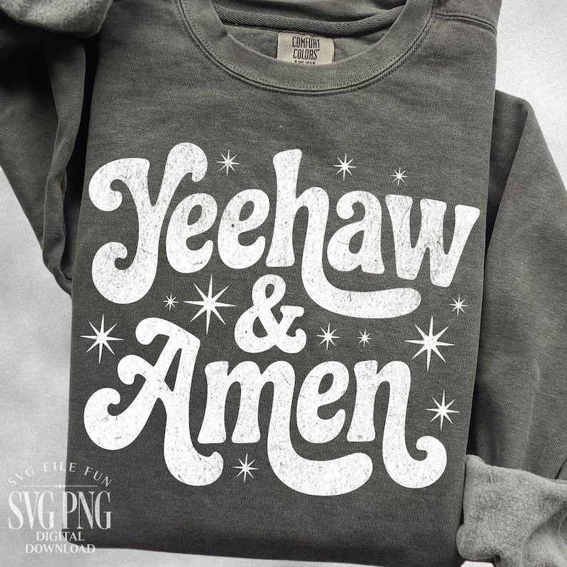 Puede incluir: Una sudadera gris oscuro con las palabras "Yeehaw & Amen" en blanco, con una fuente retro. El dise&ntilde;o incluye gr&aacute;ficos de estrellas. La sudadera est&aacute; hecha de un material suave y tiene cuello redondo.