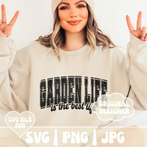 May include: A white sweatshirt with the text "GARDEN LIFE is the best life" in black with a distressed look. The text is in a large, bold font. The sweatshirt is being modeled by a person with long brown hair and a white beanie.
