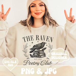 May include: A beige sweatshirt with a black and white graphic design featuring a raven perched on a stack of books. The graphic also includes the text "The Raven Poetry Club Est. 1845". The sweatshirt is being modeled by a person with long blonde hair and a white beanie.