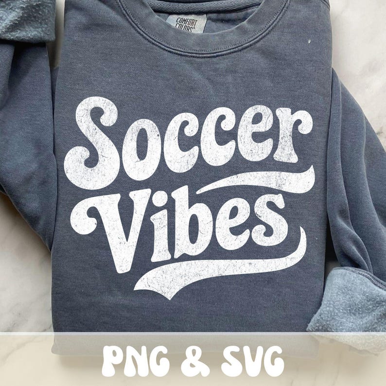 Op de afbeelding: Een donkergrijs sweatshirt met de tekst "Soccer Vibes" in grote, witte letters met een distressed look. De sweatshirt heeft een ronde hals en lange mouwen. De tekst "PNG & SVG" staat onderaan.