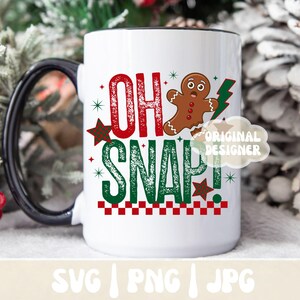 May include: White ceramic mug with a black handle and rim, featuring the text "OH SNAP!" in red and green, along with a gingerbread man and lightning bolt graphic. The mug has a festive, holiday theme.