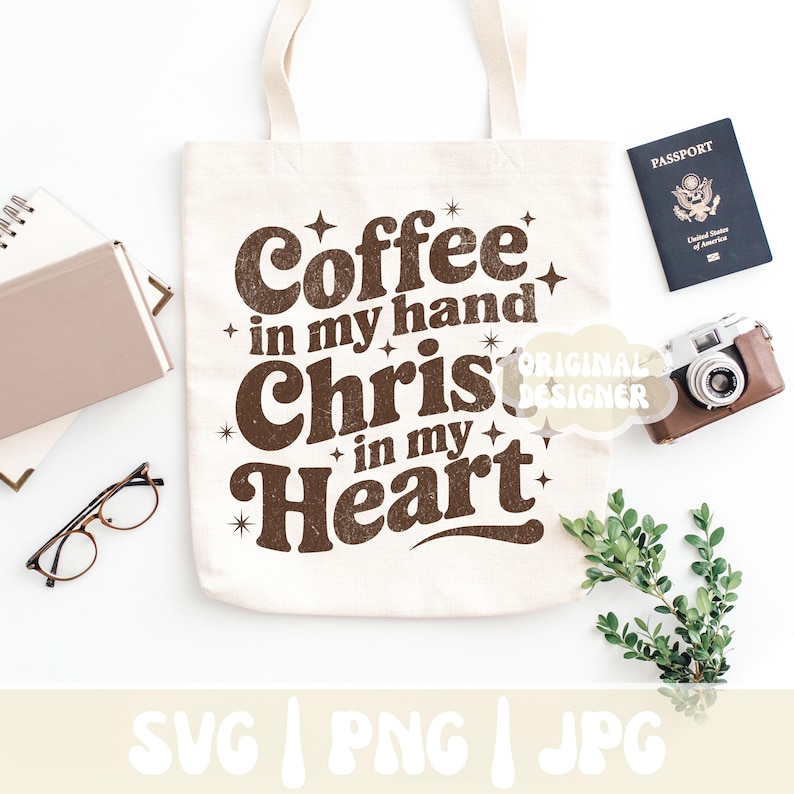 May include: Cream-colored tote bag with the text "Coffee in my hand, Christ in my heart" in brown. The bag is surrounded by a passport, a vintage camera, glasses, a notebook, and greenery. The bottom of the image has the text "SVG | PNG | JPG".