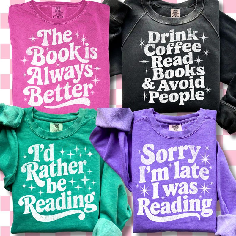 Op de afbeelding: Vier kleurrijke sweatshirts met witte tekst. Het roze sweatshirt zegt "The Book is Always Better". Het zwarte sweatshirt zegt "Drink Coffee Read Books & Avoid People". Het groene sweatshirt zegt "I'd Rather be Reading". Het paarse sweatshirt zegt "Sorry I'm late I was Reading."