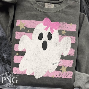Op de afbeelding: Een antracietgrijze sweater met ronde hals en een verweerde witte spookafbeelding met een roze strik op het hoofd. Het ontwerp bevat horizontale roze strepen en gouden sterren. De tekst DO NOT COPY staat op het spook gedrukt.