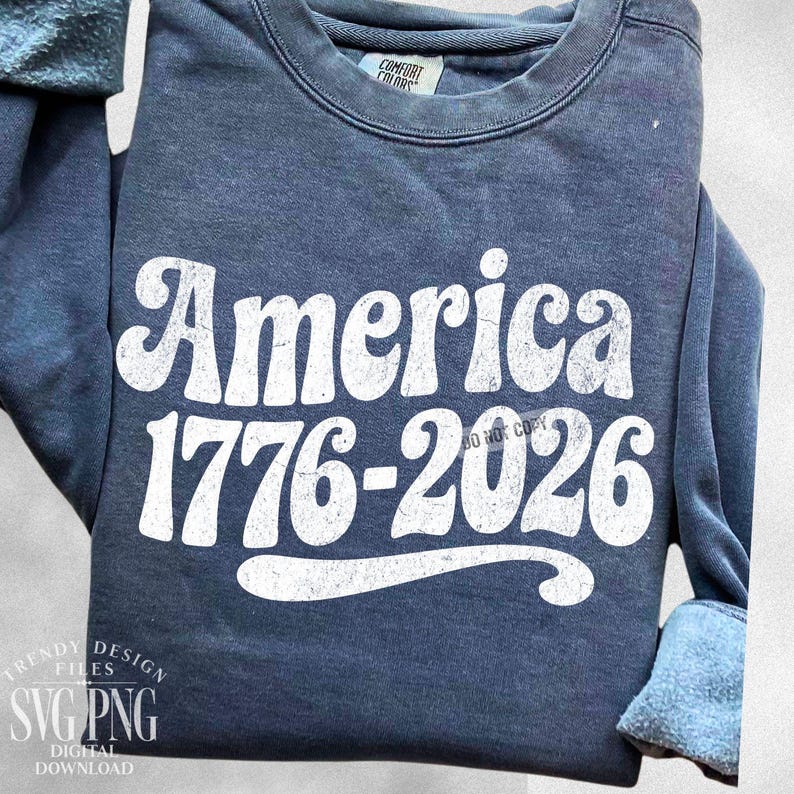 May include: A navy blue sweatshirt with the word "America" in large, white, retro-style font. Below the word "America" is the text "1776-2026" in white. The sweatshirt also has the text "DO NOT COPY" in white. The sweatshirt is from Comfort Colors.