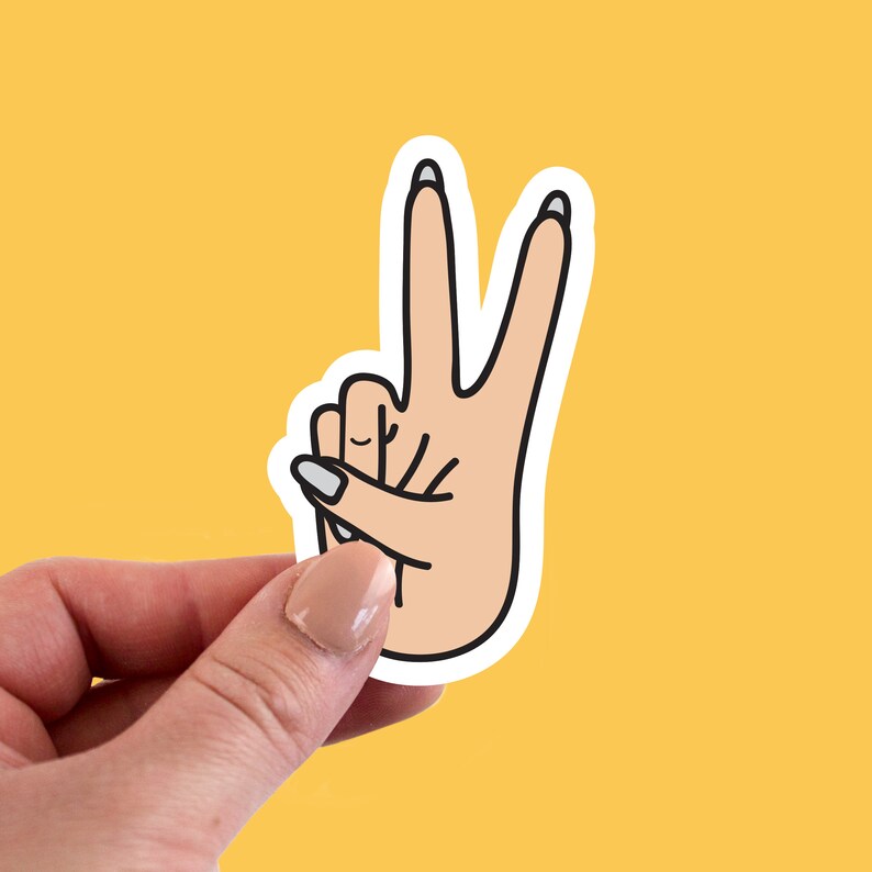 May include: A white sticker with a black outline of a hand making the peace sign. The hand is light pink with white nail polish.