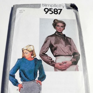 May include: A Simplicity 9587 sewing pattern envelope for a size 12 miss. The front features a photograph of a person wearing a long-sleeved brown blouse with a high neckline and a sketch of a blue long-sleeved blouse paired with a gray skirt.