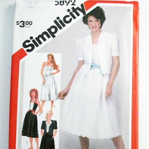 May include: Simplicity sewing pattern featuring a woman in a white dress and jacket. The pattern includes illustrations of different dress styles. The package is white with red accents and the Simplicity logo.