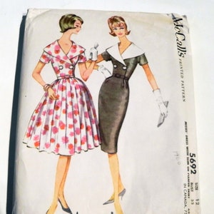 May include: Vintage McCall's printed sewing pattern featuring illustrations of two dresses. One dress is a floral print with a full skirt, and the other is a sheath dress with a contrasting collar. The pattern number is 5692.