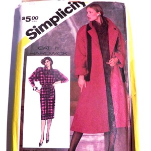 May include: A vintage Simplicity sewing pattern featuring a woman in a long, red coat with black trim. The pattern includes a plaid dress design by Cathy Hardwick. The price is $5.00.