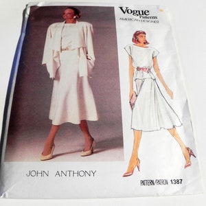 May include: A Vogue Patterns American Designer sewing pattern envelope for John Anthony design 1387. The front features a photograph and a fashion illustration of a two-piece outfit consisting of a short-sleeved top and a flared skirt.