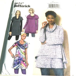May include: A sewing pattern package featuring a woman modeling a layered gray and white sweater with a cowl neck. The package includes illustrations of other tunic-style tops. The pattern number is B6247.
