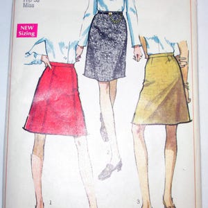 May include: Vintage Simplicity sewing pattern featuring three skirt designs. The pattern includes waist 27 and hip 38 sizing. The cover displays illustrations of the skirts in red, black, and yellow. The text "Simplicity" is prominently displayed.