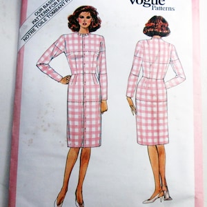 May include: A Vogue Patterns sewing pattern envelope for a dress, labeled 1000. The illustration shows a long-sleeved, knee-length dress with a pink and white gingham check pattern, a high neckline, and a button-front closure, displayed from front and back views.