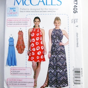 May include: McCall's sewing pattern M7405 for dresses. The pattern features illustrations of various dress styles, including a red halter dress with white circular patterns and a long blue and black patterned dress. The package includes instructions for beginners.