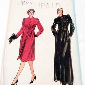 May include: A Vogue Patterns sewing pattern envelope for size 6, featuring illustrations of two long-sleeved coats. One is a knee-length red coat with buttons, and the other is a floor-length black coat. The text includes 'vogue Patterns', 'SIZE 6', '1990's', and 'PAID'.