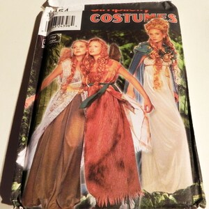 May include: Simplicity Costumes pattern envelope featuring three women in fantasy gowns. The gowns are in shades of brown, orange, and white, with decorative elements. The background shows a forest scene. The envelope has a barcode and the number 9454.