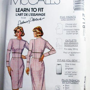 May include: A McCall's Learn to Fit sewing pattern envelope, number 2718, size 22. The white paper package features illustrations of a person wearing a long-sleeved, pink and white gingham dress with a high neckline and black seam detailing.
