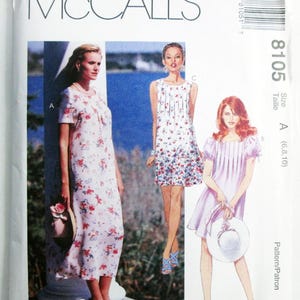 May include: A McCall's 8105 sewing pattern envelope featuring three dress variations. The designs include a long floral dress, a short floral dress, and a short solid light purple dress with puffed sleeves, all displaying pleated necklines.