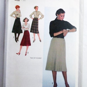 May include: A Simplicity 9176 sewing pattern envelope for a size 14, 28-inch waist skirt. The front features illustrations of three skirt variations and a photograph of a person wearing a pleated beige skirt with a black long-sleeve top.
