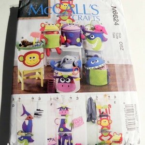 May include: A McCall's Crafts sewing pattern featuring various animal-themed storage containers and organizers. The pattern includes designs for monkey, shark, cow, and giraffe-shaped storage solutions, with the pattern number M6624 visible.