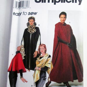 May include: A Simplicity 7438 sewing pattern envelope featuring illustrations of four different cape styles labeled A, B, C, and D. The designs include a long red cape, a black cape with a leopard print scarf, a short red cape, and a gold wrap.