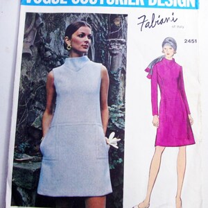 May include: Vogue Couturier Design pattern featuring a sleeveless light blue dress with pockets and a high neckline. The illustration shows a magenta long-sleeve dress with a similar design. The pattern is labeled "Fabiani of Italy" and includes the number 2451.