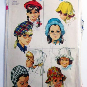 May include: Vintage Simplicity sewing pattern 7977 for children's hats. The pattern features illustrations of various hat styles, including a red beret, a yellow flower-shaped hat, and a blue bonnet. The text on the pattern reads "Child Size 21" and "Simplicity".