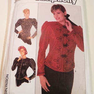 May include: Simplicity sewing pattern featuring three jacket designs. The jackets have long sleeves and decorative closures. The pattern envelope shows a woman wearing a red jacket with black trim and a black skirt. The Simplicity logo is at the top.