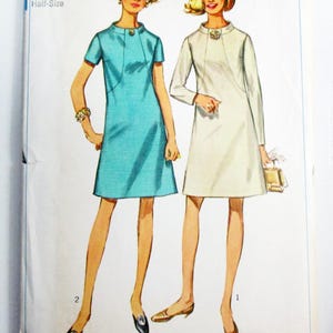 May include: Vintage Simplicity sewing pattern 7807 featuring two women in dresses. The pattern includes a turquoise dress with short sleeves and a white dress with long sleeves. The pattern is size 16 1/2 with a bust of 39 inches.