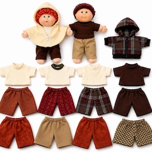 May include: Two dolls with round faces and yarn hair, one with red hair wearing a cream hooded cape and brown pants, the other with brown hair wearing a brown shirt and tan pants. Includes a plaid hoodie and various shirts and shorts.