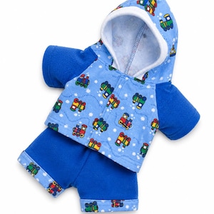 May include: A blue baby's or toddler's hooded jacket and shorts set. The jacket and shorts are blue with a pattern of colourful toy trains and white stars. The hood has a white lining.