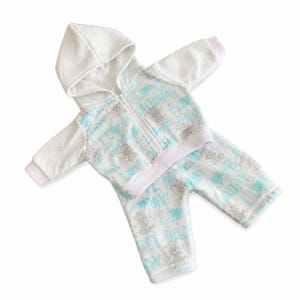 May include: A baby's two-piece outfit, featuring a white hooded zip-up jacket and matching pants. The set is patterned with gray elephants, blue hearts, and the words "I LOVE MOMMY" and "I LOVE DADDY" on a white background.