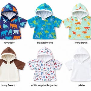 May include: Six short-sleeved hooded shirts in various patterns and colors. Top row: navy tiger print, blue palm tree print, and ivory fox print. Bottom row: brown and ivory raglan, white vegetable garden print, and a solid white shirt.