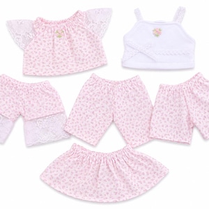 May include: A set of doll clothing including a pink floral top with lace sleeves, a white tank top with a floral accent, two pairs of pink floral shorts, one pair of pink floral shorts with lace trim, and a pink floral skirt with an elastic waistband.