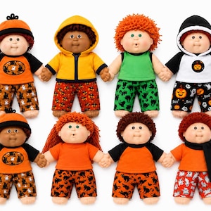 May include: Eight dolls arranged in two rows, each wearing Halloween-themed outfits. The dolls feature various hair colors, skin tones, and clothing including orange, black, green, and yellow shirts, hoodies, hats, and patterned shorts with ghosts and pumpkins.
