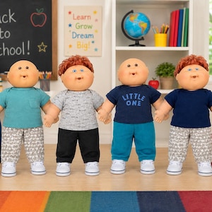 May include: Four dolls with round faces and yarn hair, wearing casual outfits. The first wears a teal shirt and patterned pants, the second a grey patterned shirt and black pants, the third a navy shirt with 'LITTLE ONE' text and teal pants, and the fourth a navy shirt and patterned pants.