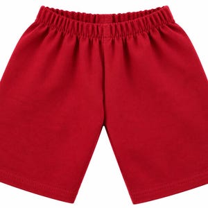 Peut inclure: Un short rouge uni doté d'une taille élastique avec des détails de tissu froncé. Le short présente une coupe droite simple qui arrive à mi-cuisse, avec des ourlets propres et finis au bas de chaque ouverture de jambe.