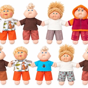 May include: A collection of nine dolls with yarn hair, round faces, and rosy cheeks. Each doll wears different outfits, including patterned shirts with fox prints, solid brown shirts, white shirts, and hooded jackets, paired with shorts in orange, brown, or plaid.