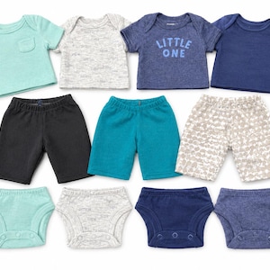 May include: A collection of baby clothing including four short-sleeved shirts, three pairs of shorts, and four nappy covers. The items feature solid colours in mint, black, teal, and navy, alongside heather grey and patterned fabrics with the text LITTLE ONE.