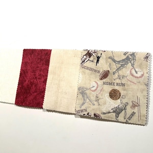 May include: A collection of fabric swatches. One swatch is white with a subtle pattern, another is burgundy with a textured appearance, and a third is beige. The final swatch features sports-themed illustrations of football, baseball, and basketball.