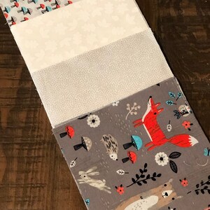 May include: Four fabric squares with different woodland animal and nature patterns. The top square has a white background with red and blue mushrooms. The second square is white with a subtle floral pattern. The third square is gray with a subtle speckled pattern. The bottom square is gray with a fox, hedgehog, rabbit, and bear.