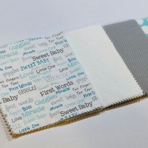 May include: A stack of three fabric swatches. The top swatch is light blue with white clouds. The middle swatch is gray with a textured pattern. The bottom swatch is white with a repeating pattern of blue and gray words, including "Sweet Baby", "First Words", "Giggles", and "Miracle".