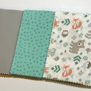 May include: Three fabric squares with different patterns. The first square is orange with a chevron pattern. The second square is gray. The third square is green with white dots. The fourth square is white with a pattern of foxes, owls, bears, hedgehogs, mushrooms, and green geometric shapes.