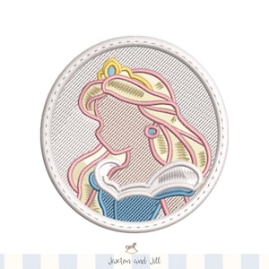 Pode incluir: Design bordado de uma princesa em uma moldura circular. A princesa tem cabelo loiro longo e esvoaçante, uma coroa de ouro e um vestido azul. O desenho é costurado com fio rosa, amarelo e azul sobre um fundo cinza claro. O texto "Jaxton and Jill" está na parte inferior.